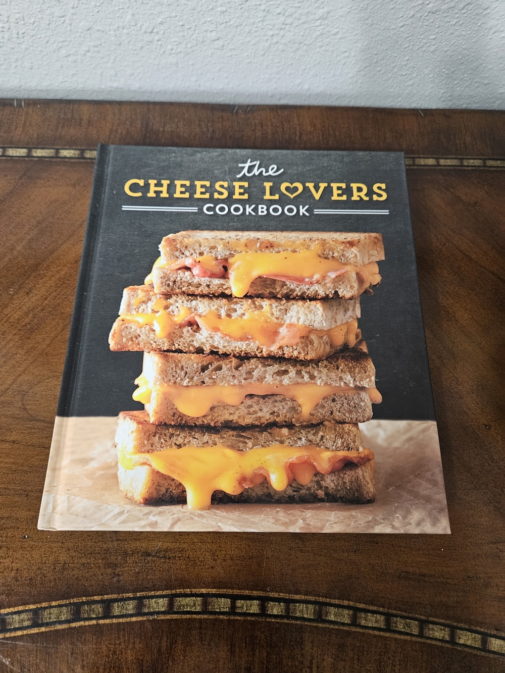 The Cheese Lovers Cookbook - Black Cover with Cheddar Grilled Cheese Image